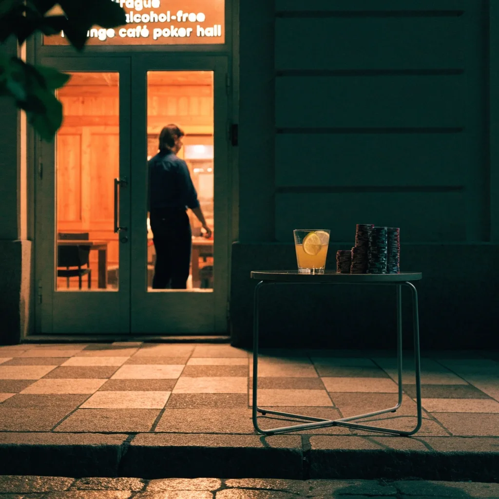 Herna ve večerním světle s prázdnými židlemi u stolů a prosvětleným vchodem do lounge